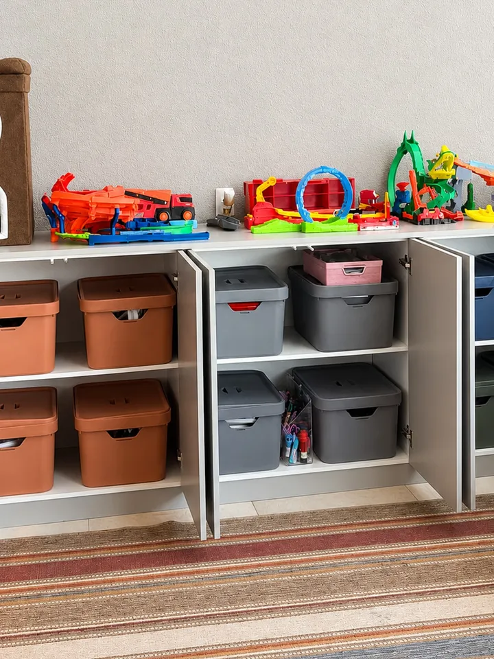 Armário de brinquedos com caixas iguais por cor em cada porta, brinquedos maiores expostos em cima