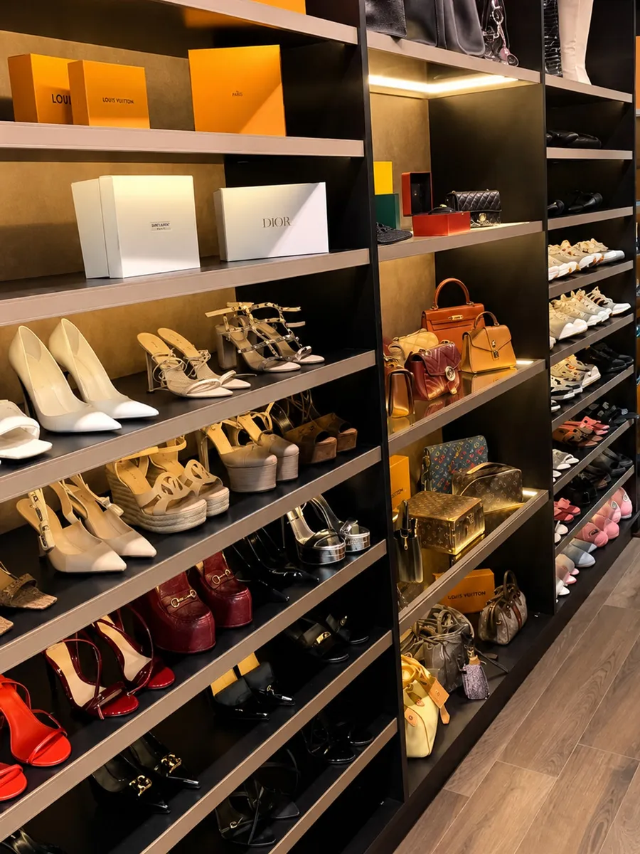 Closet organizado pela Alê: sapatos alinhados por tom em prateleiras iluminadas, bolsas e caixas em nichos